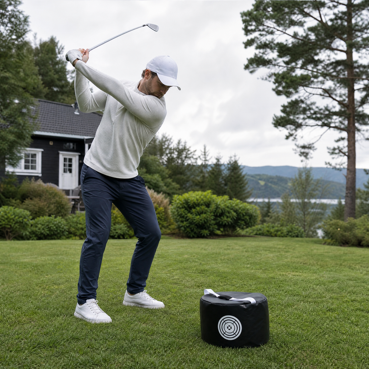 Mann på topp av backswing med golf treningsbag i hagen